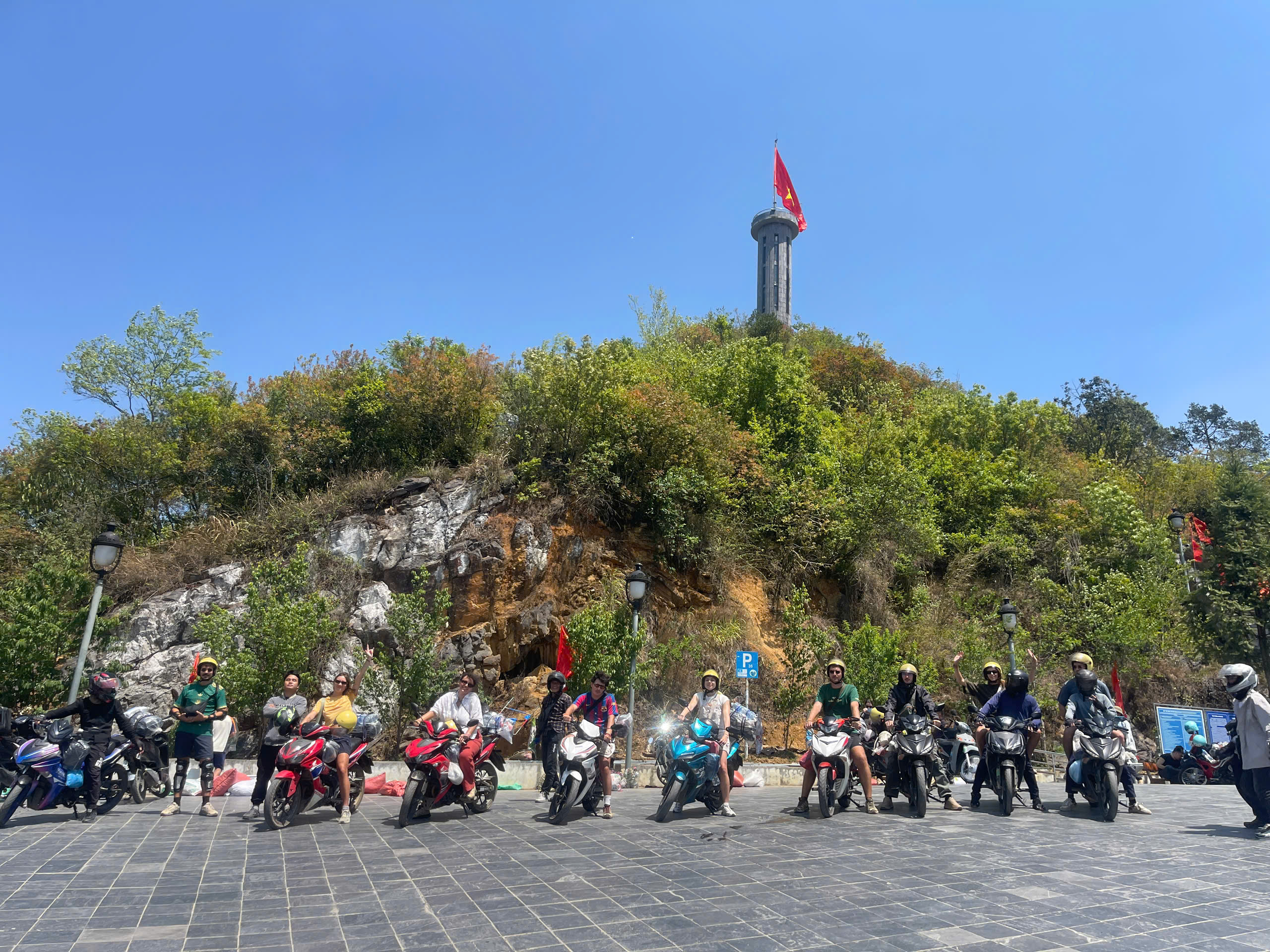 Tourists sitting on the motorbike under Lung Cu Flag tower